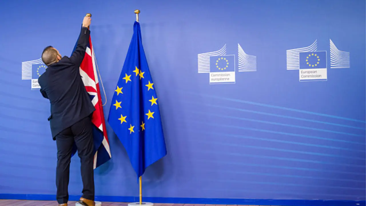 An EU official hangs the Union Jack next to the European Union flag at the VIP entrance at the European Commission headquarters in Brussels on Tuesday, Feb. 16, 2016. British Prime Minister David Cameron is visiting EU leaders two days ahead of a crucial EU summit.  (AP Photo/Geert Vanden Wijngaert)
