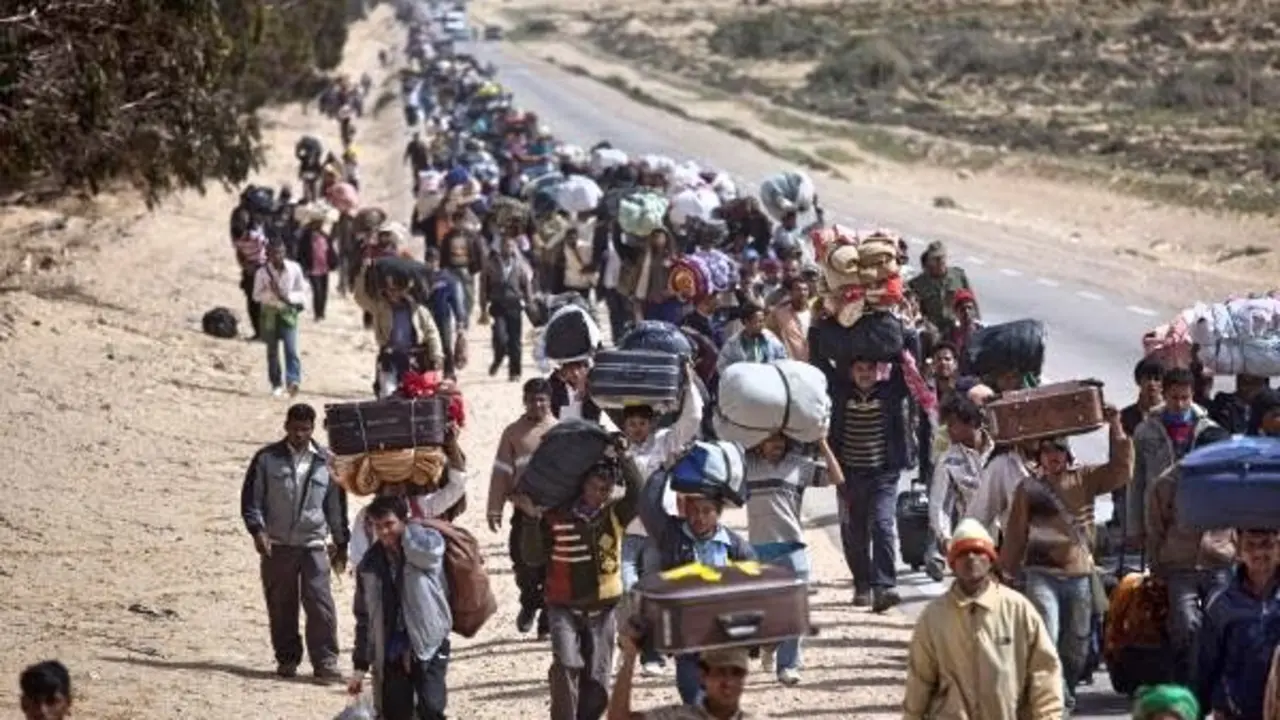 FOR USE AS DESIRED, YEAR END PHOTOS - FILE -In this March 4, 2011 file photo, men from Bangladesh, who used to work in Libya but recently fled the unrest, walk with their belongings alongside a road, as they head to a refugee camp after crossing the Tunisia-Libyan border, in Ras Ajdir, Tunisia. (AP Photo/Emilio Morenatti, File)