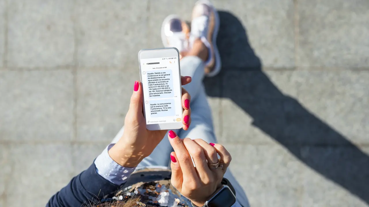 Woman using instant messaging app on mobile phone, view from above