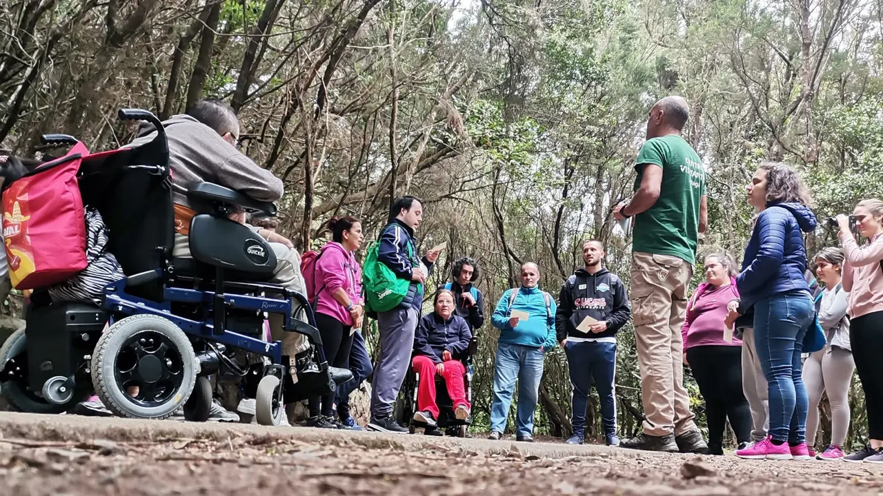 El Centro de Visitantes de Cruz del Carmen ofrece rutas por Anaga para personas con diversidad funcional
En el Parque Rural existen dos recorridos adaptados, el tramo 1 del sendero de los sentidos y el sendero accesible de la Pista de las Hiedras
El Centro de Visitantes de Cruz del Carmen, en el Parque Rural de Anaga, ofrece desde la entrada de la primavera la segunda edici&oacute;n del programa Ruta Pasapanaga, una iniciativa que propone un recorrido por el tramo adaptado de la Pista de las Hiedras en el que personas con diversidad funcional pueden adentrarse en el coraz&oacute;n del Monteverde para conocer los valores naturales y culturales del Parque Rural de Anaga y as&iacute; poder entender su pasado, su presente y la importancia que tiene su conservaci&oacute;n. Todo ello a trav&eacute;s de actividades conducidas por los gu&iacute;as del parque en las que la participaci&oacute;n y el uso de los sentidos son claves.

&ldquo;La atenci&oacute;n a la diversidad es un reto en la gesti&oacute;n de los espacios naturales, es por ello que tanto en Anaga como en otros espacios naturales estemos implementando tramos o senderos completos adaptados a necesidades especiales&rdquo;, ha indicado la consejera de Gesti&oacute;n del Medio Natural, Isabel Garc&iacute;a. En el caso del Parque Rural de Anaga, &ldquo;el equipo de gu&iacute;as del Centro de Visitantes de Cruz del Carmen desarrolla un interesante trabajo con asociaciones y grupos que lo solicitan para poder acercar a la ciudadan&iacute;a ofertas accesibles relacionadas con este entorno tan exclusivo como es el macizo de Anaga&rdquo;, se&ntilde;al&oacute; la consejera.

El recorrido de aproximadamente dos kil&oacute;metros ida y vuelta y sus paradas permiten comprender como la palabra Anaga contiene todos los elementos que hacen de este paisaje un lugar &uacute;nico y especial. A lo largo de los &uacute;ltimos dos meses los gu&iacute;as del centro de visitantes han realizado esta actividad con varios colectivos y asociaciones como Coordicanarias, Asocide, conformado por personas con sordoceguera, Asmipuerto, que atiende a personas con diferentes tipos de diversidad funcional, Funcasor, personas sordas del centro residencial &ldquo;En compa&ntilde;&iacute;a&rdquo;, y Cruz Roja de Icod y Tacoronte, con personas usuarias del proyecto de Atenci&oacute;n a cuidadores/as de pacientes con discapacidad.

Desde el parque se ha hecho un gran esfuerzo para hacer accesible el territorio y su disfrute a todas las personas. Existen dos senderos adaptados como son el tramo 1 del sendero de los sentidos y el sendero accesible de la Pista de las Hiedras. 

La iniciativa de la ruta guiada Pasapanaga pretende ser un paso m&aacute;s en esta direcci&oacute;n acercando la Educaci&oacute;n Ambiental y la interpretaci&oacute;n del patrimonio a las personas que habitualmente suelen tener m&aacute;s dificultades para hacerlo.