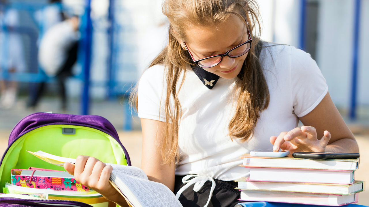 Portrait of a schoolgirl with glasses on the street
