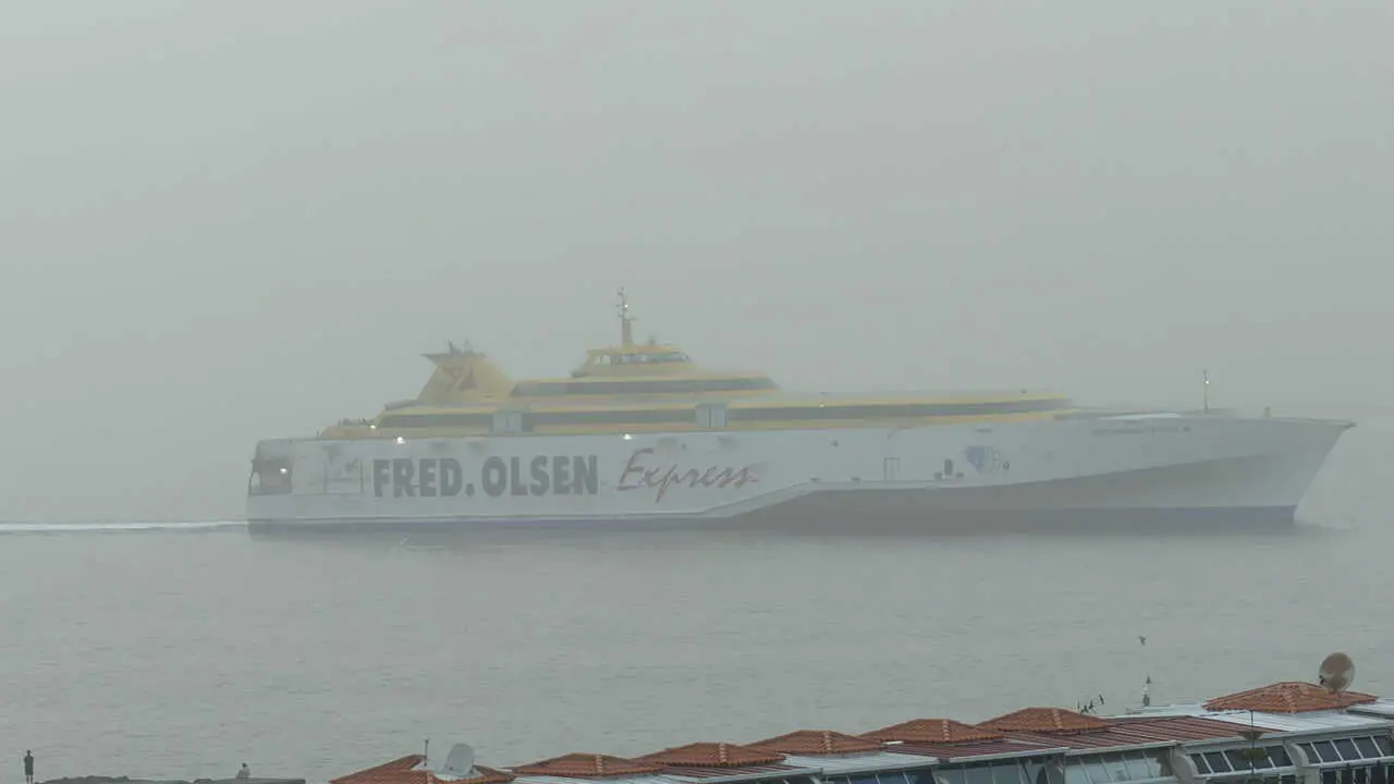 El Fred Olsen Express lega a puerto en Los Cristianos bajo la intensa calima. Foto Esteban P&eacute;rez
